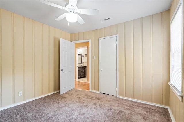 unfurnished bedroom with ceiling fan, multiple windows, and light colored carpet