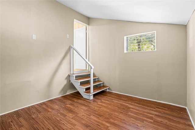 staircase with hardwood / wood-style floors and vaulted ceiling