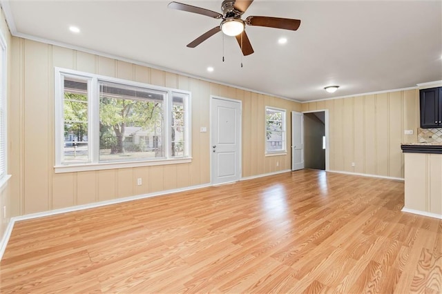 unfurnished living room featuring light hardwood / wood-style floors, crown molding, and ceiling fan