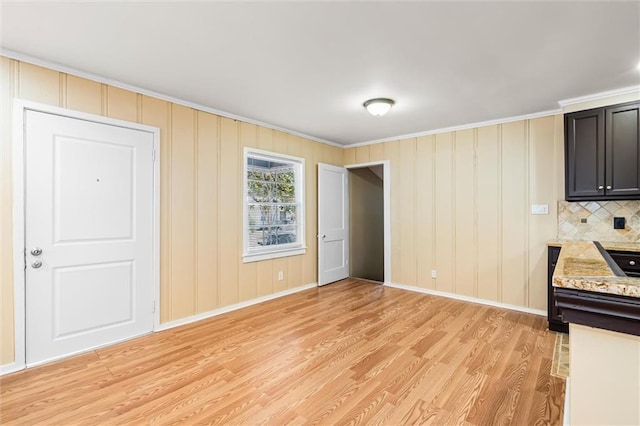 kitchen featuring decorative backsplash, light stone counters, crown molding, and light hardwood / wood-style floors