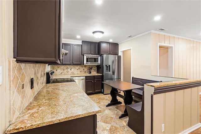 kitchen with backsplash, dark brown cabinets, light stone counters, stainless steel appliances, and crown molding