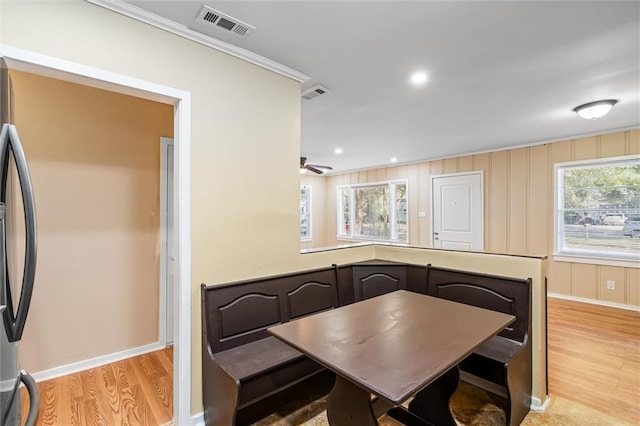 dining space with light hardwood / wood-style flooring, ornamental molding, and a healthy amount of sunlight