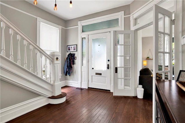 foyer entrance with dark wood-type flooring, baseboards, and stairway