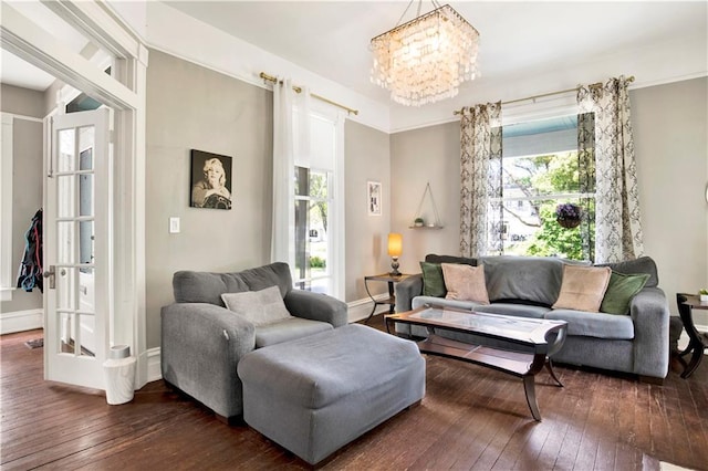 living room with dark wood-style flooring, baseboards, and an inviting chandelier