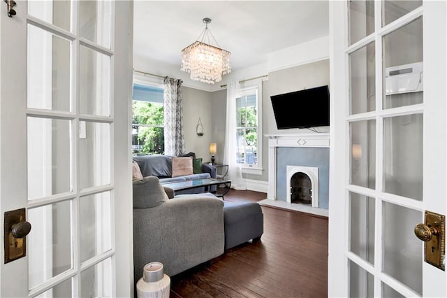 living room with dark wood-type flooring, a chandelier, and a fireplace