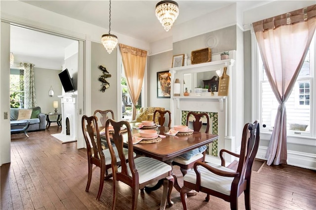dining space with dark wood-type flooring, a fireplace, and a notable chandelier