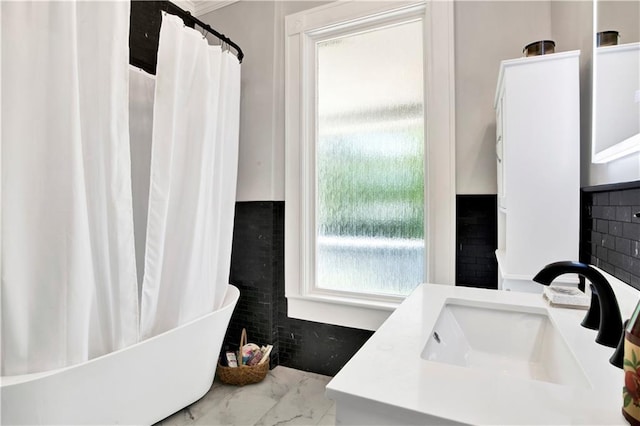 full bathroom featuring a soaking tub, marble finish floor, vanity, and a shower with curtain