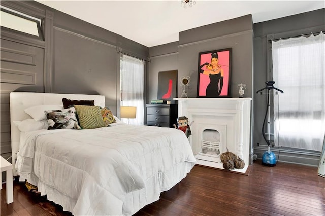 bedroom with a fireplace and dark wood-style floors