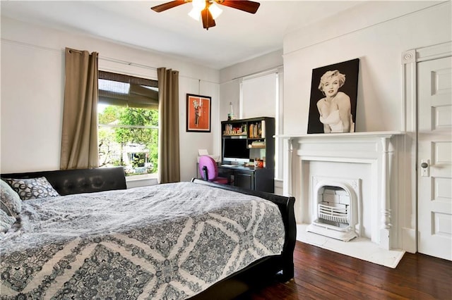 bedroom with a fireplace with flush hearth, ceiling fan, and wood finished floors