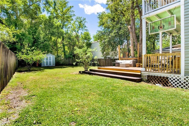 view of yard with a storage shed, a fenced backyard, a deck, and an outdoor structure