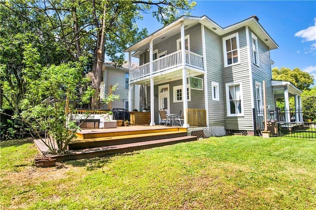 back of property with a yard, fence, and a balcony