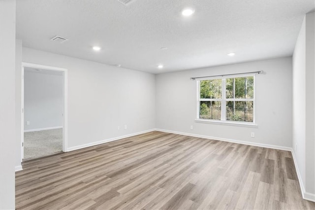 spare room with a textured ceiling and light wood-type flooring