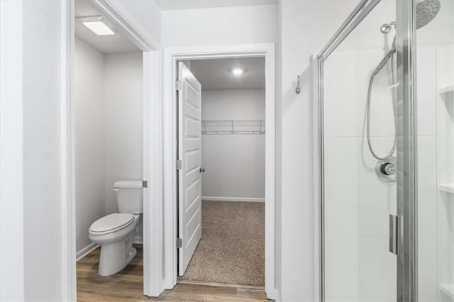 bathroom with toilet, walk in shower, and hardwood / wood-style flooring