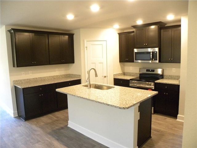 kitchen with sink, an island with sink, stainless steel appliances, and wood-type flooring