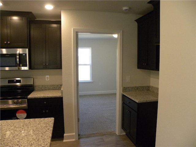 kitchen with dark hardwood / wood-style floors, light stone counters, and stainless steel appliances