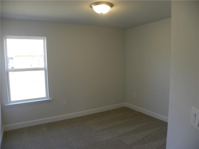 spare room with plenty of natural light and dark colored carpet