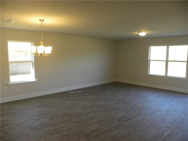 spare room with dark wood-type flooring and a notable chandelier