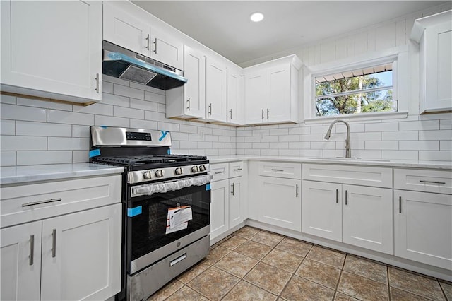 kitchen featuring decorative backsplash, white cabinetry, stainless steel gas range oven, and sink