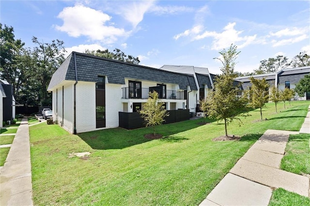 back of house with a balcony and a lawn