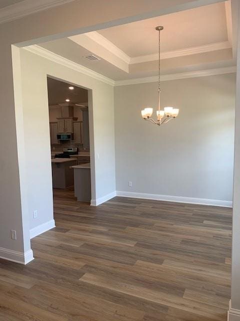 spare room with dark wood-type flooring, ornamental molding, a tray ceiling, and a chandelier