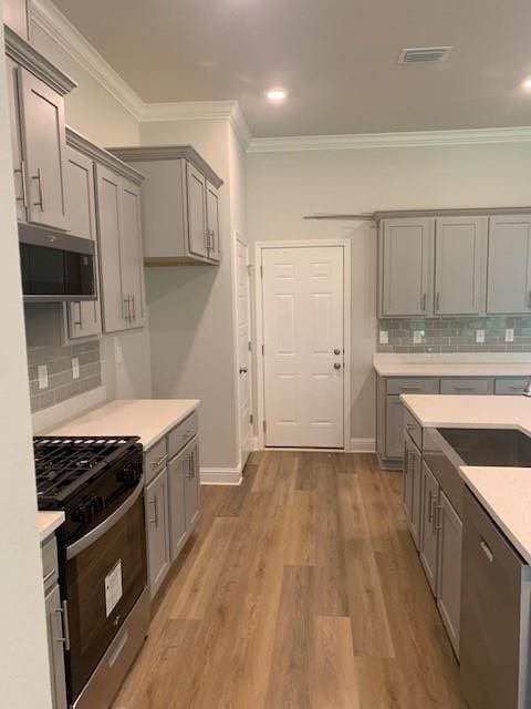 kitchen featuring stainless steel appliances, ornamental molding, and gray cabinets