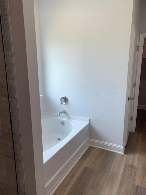 bathroom with hardwood / wood-style floors and a tub to relax in