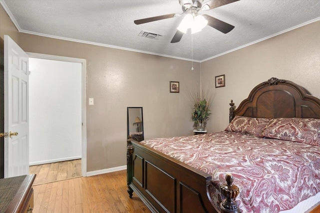 bedroom with a textured ceiling, light wood-type flooring, ceiling fan, and ornamental molding