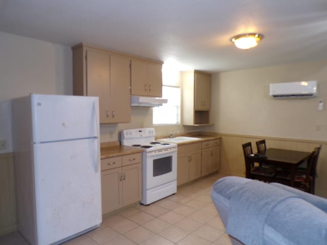 kitchen featuring under cabinet range hood, white appliances, light countertops, cream cabinetry, and a wall mounted AC