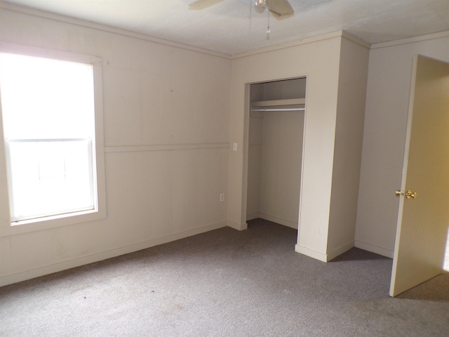 unfurnished bedroom with baseboards, a ceiling fan, ornamental molding, carpet, and a closet