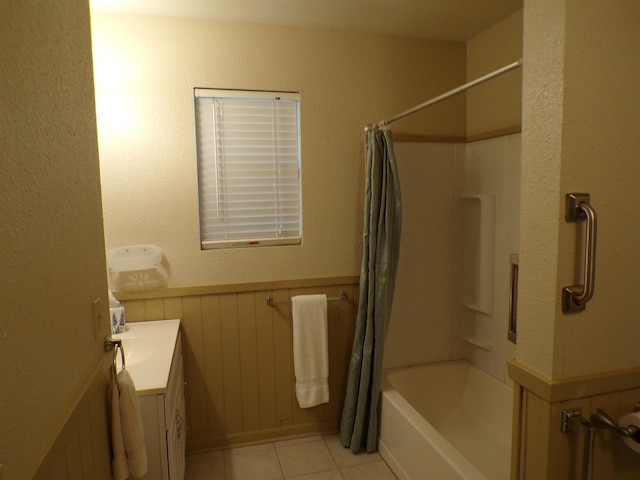 full bathroom with tile patterned flooring, a wainscoted wall, shower / bathtub combination with curtain, and vanity