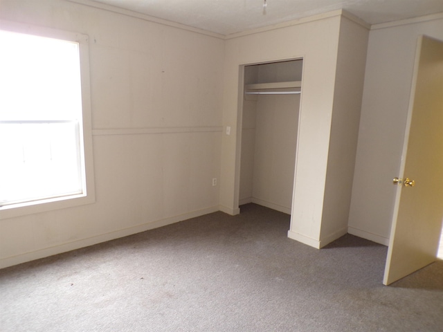 unfurnished bedroom featuring a closet, carpet flooring, and crown molding