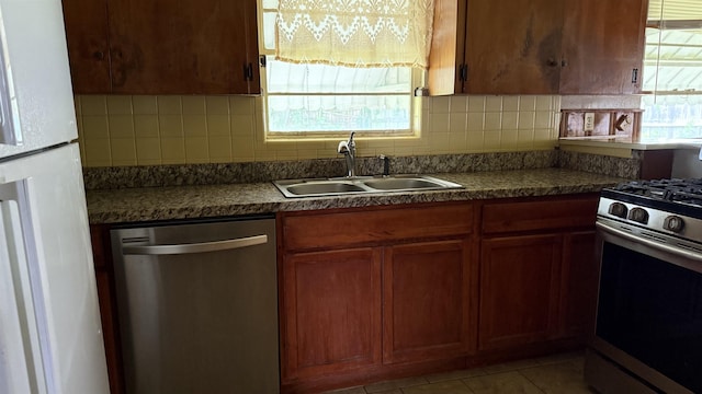 4011 Everglades Ave, Port Arthur, TX 77642 - kitchen with stainless steel appliances, tasteful backsplash, light tile patterned flooring, and brown cabinetry