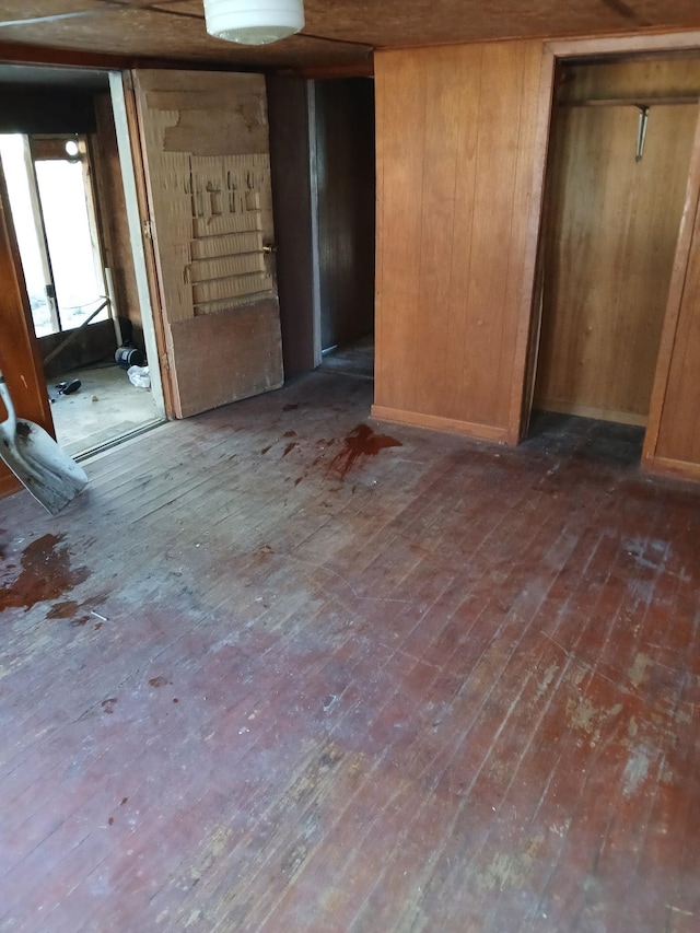 unfurnished bedroom with dark wood-style flooring and wood walls