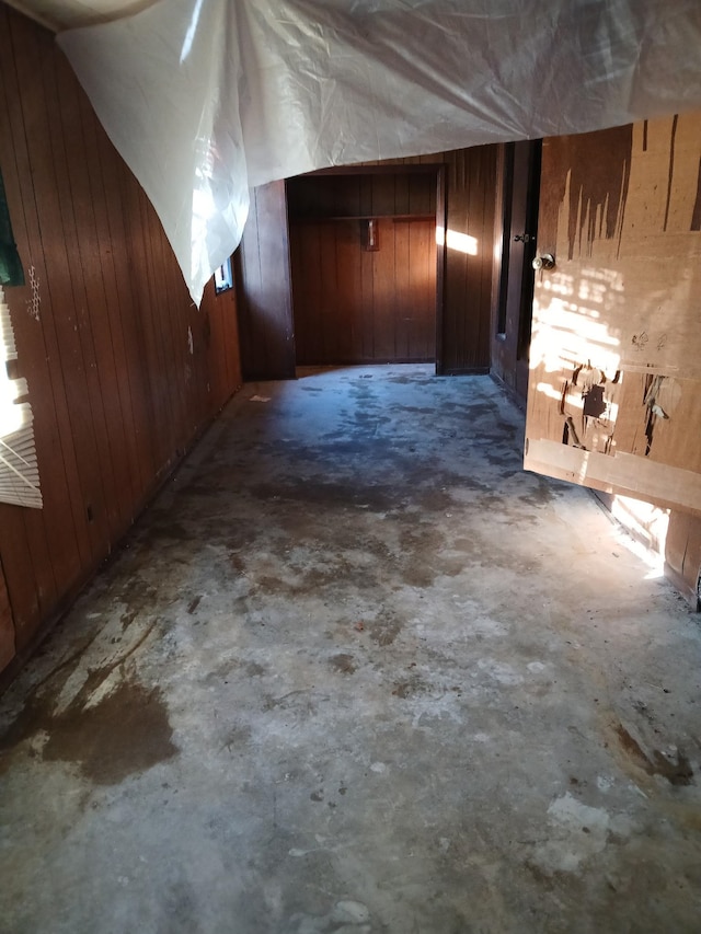 bonus room featuring wood walls and concrete flooring