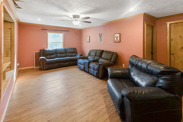 living room featuring a textured ceiling, light hardwood / wood-style floors, ceiling fan, and crown molding