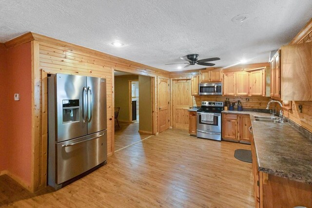 kitchen featuring light wood-type flooring, a textured ceiling, stainless steel appliances, ceiling fan, and sink