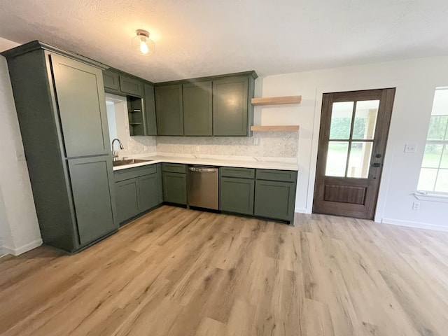 kitchen featuring open shelves, a sink, light wood finished floors, stainless steel dishwasher, and green cabinets