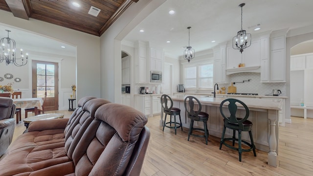 living room with wooden ceiling, ornamental molding, and light hardwood / wood-style floors