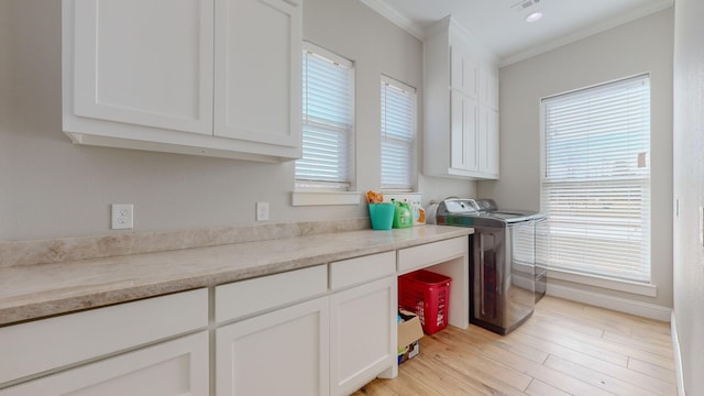 laundry room featuring washing machine and dryer, cabinets, ornamental molding, and light hardwood / wood-style flooring