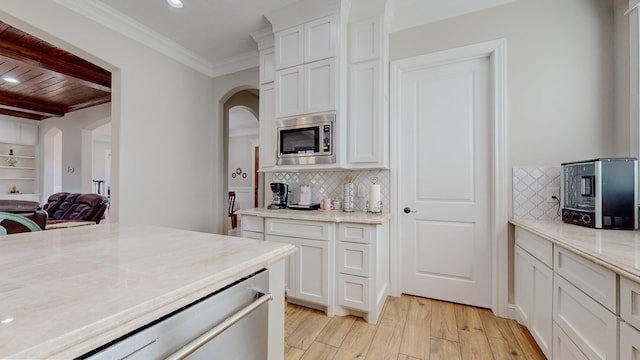 kitchen with stainless steel microwave, decorative backsplash, white cabinetry, and light hardwood / wood-style flooring