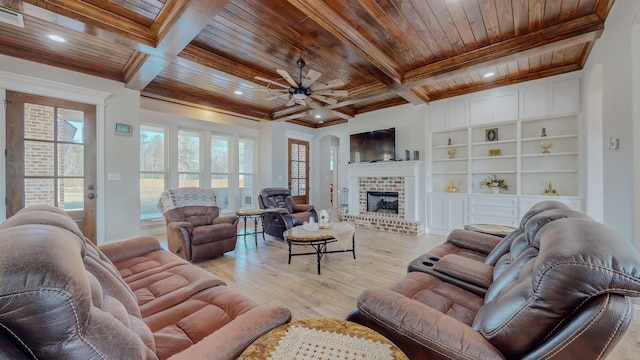 living room with wood ceiling, a brick fireplace, ceiling fan, light wood-type flooring, and built in features