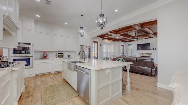 kitchen featuring sink, coffered ceiling, white cabinetry, appliances with stainless steel finishes, and an island with sink