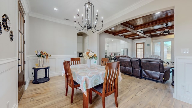 dining space with light wood-type flooring, ornamental molding, ceiling fan with notable chandelier, and coffered ceiling