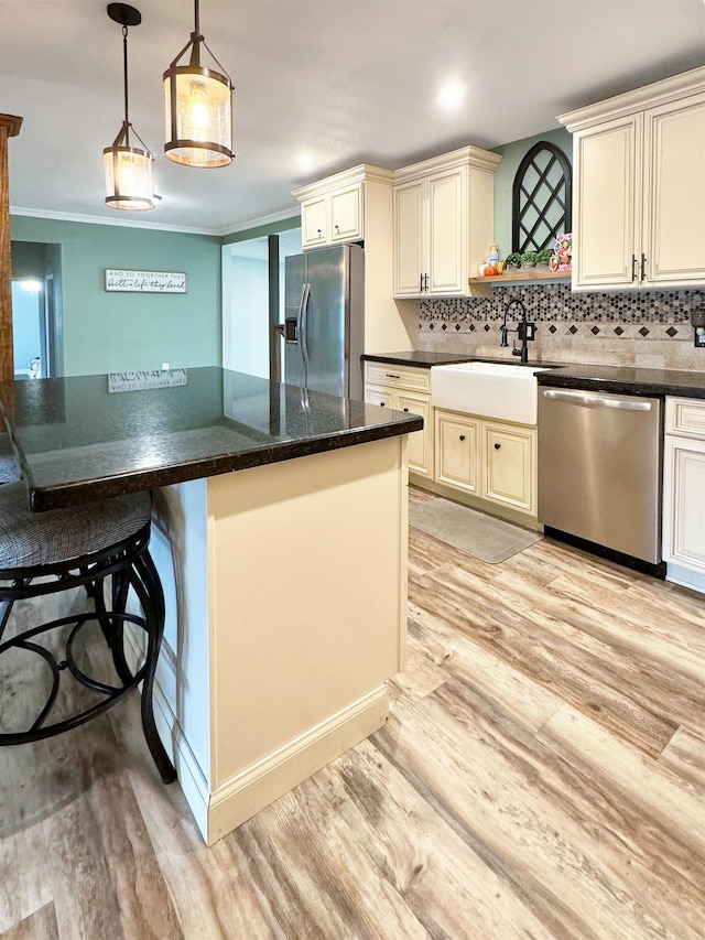 kitchen with sink, appliances with stainless steel finishes, light wood-type flooring, and cream cabinets