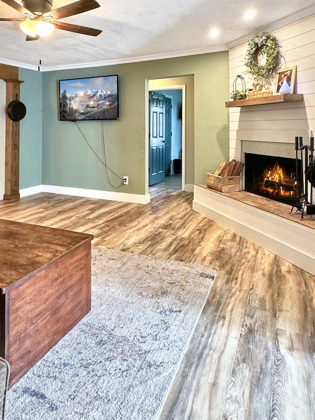 living room with crown molding, ceiling fan, a textured ceiling, and hardwood / wood-style flooring