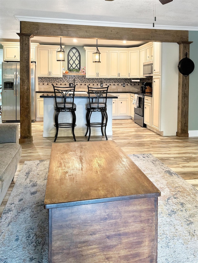 kitchen with a kitchen breakfast bar, pendant lighting, stainless steel appliances, and light wood-type flooring