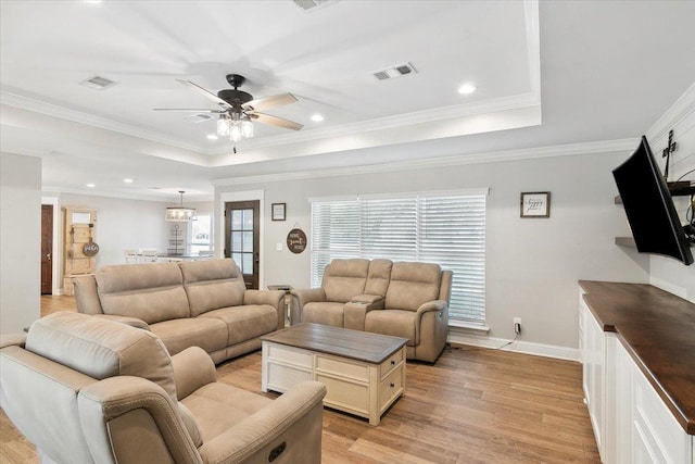 living room featuring ceiling fan with notable chandelier, light hardwood / wood-style flooring, a raised ceiling, and crown molding