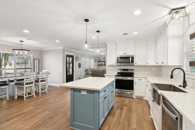 kitchen with white cabinets, decorative light fixtures, backsplash, and appliances with stainless steel finishes