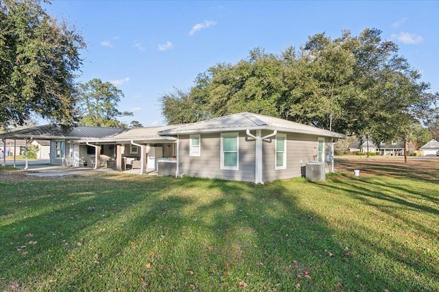 back of house with central AC unit and a yard