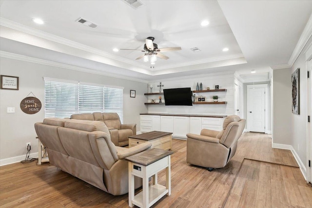 living room featuring light hardwood / wood-style flooring, a raised ceiling, ceiling fan, and crown molding